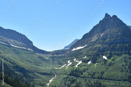 Green and Snow Dusted Mountains Surrounding Valley with Waterfall, Going-to-the-Sun Road, Glacier National Park, Montana	