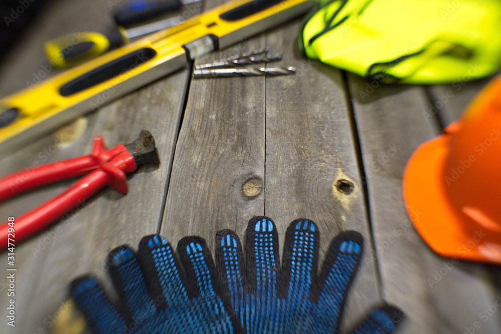 Tools on the old table.  On the table is: construction gloves, clippers, building level, drills, vest, helmet.