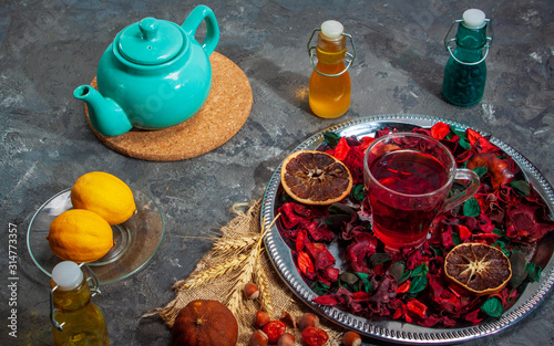 Red Hot Hibiscus tea in a glass mug on a wooden table among rose petals and dry tea custard with carcade photo