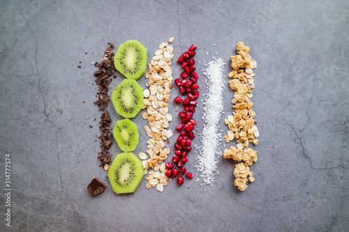 Vegan and organic ingredients for a healthy snack: Kiwi, pomegranate, chocolate, coconut, oats and grains. Top view.