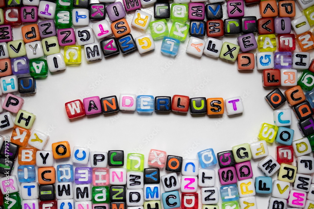 The word WANDERLUST written on colorful cubes isolated on a white background with a lot of colorful letters lying around