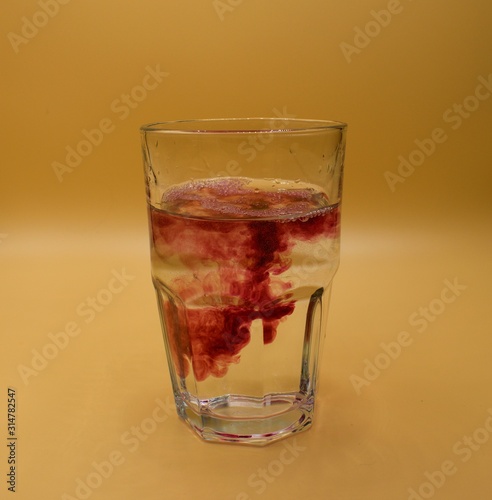 Glass of water with burst of color from water enhancer