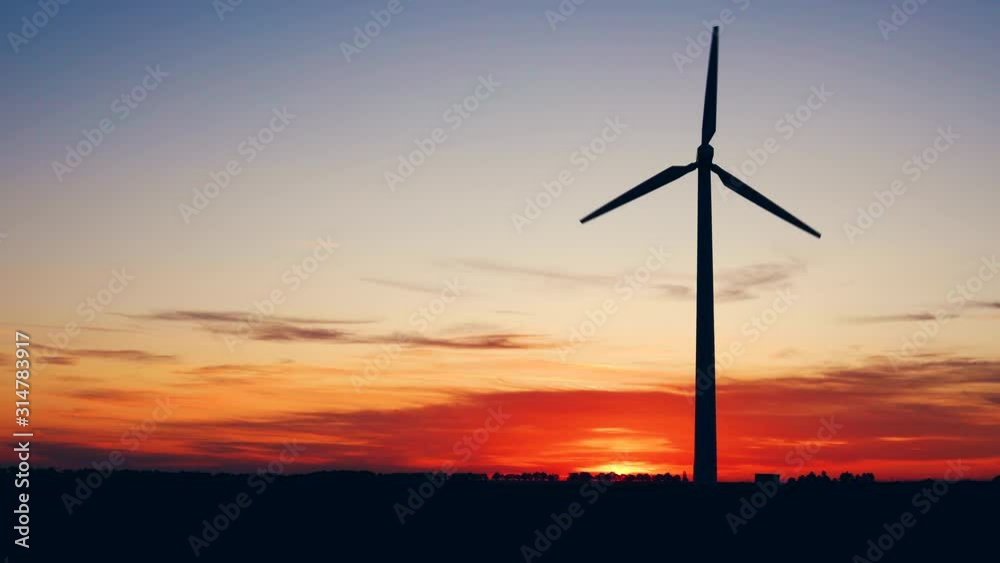Windmills for electric power production at sunset in a field Windmills for electric power production at sunset in a field