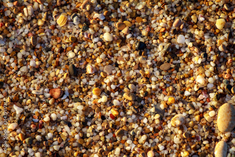 sea pebbles colored granite on the beach background stones. The shore of the beach with sand and pebbles washed by the waves of the sea. sea pebbles colored granite on the beach background stones. The shore of the beach with sand and pebbles washed by the waves of the sea.