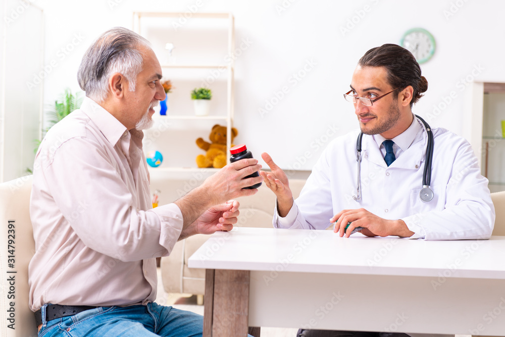 Obraz premium Young male doctor visiting old patient at home