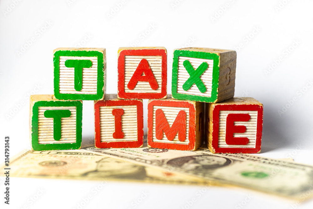 Tax Time - United States of America - wooden letters with US Dollars on white background. Shallow depth of field, selective focusing Tax Time - United States of America - wooden letters with US Dollars on white background. Shallow depth of field, selective focusing