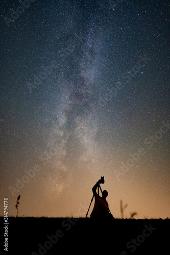 a photographer photographs the center of the milky way at clear starry sky