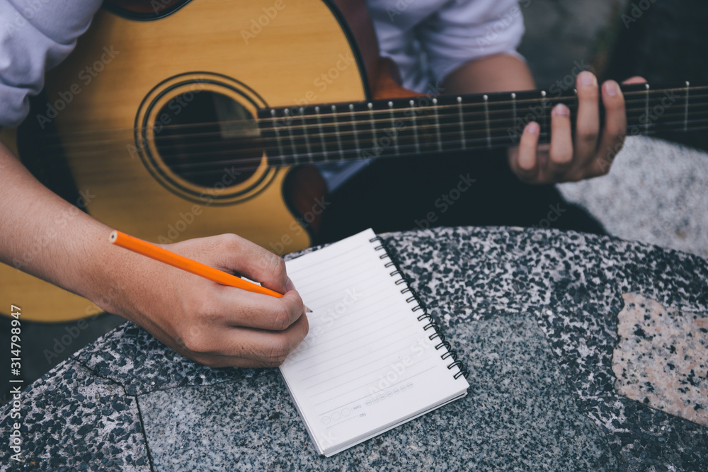 Fototapeta premium artist songwriter thinking writing notes,lyrics in book at studio.man playing live acoustic guitar relax chill.concept for musician creative.composer work process.people relaxing time with instrument
