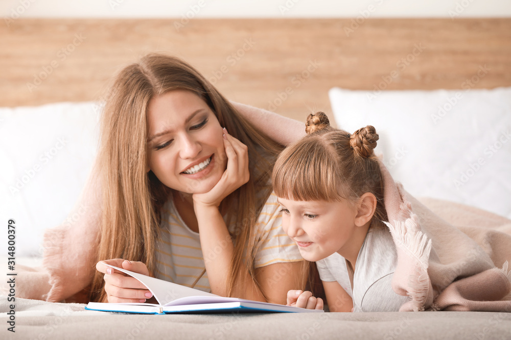 Beautiful young woman and her little daughter reading book at home Beautiful young woman and her little daughter reading book at home