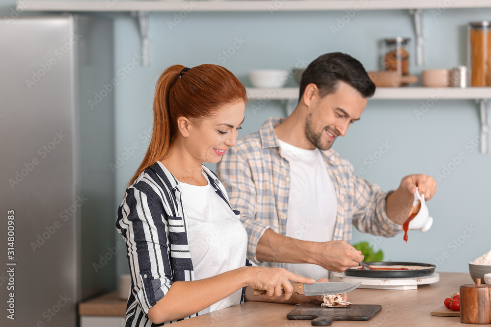 Obraz premium Happy couple cooking together in kitchen