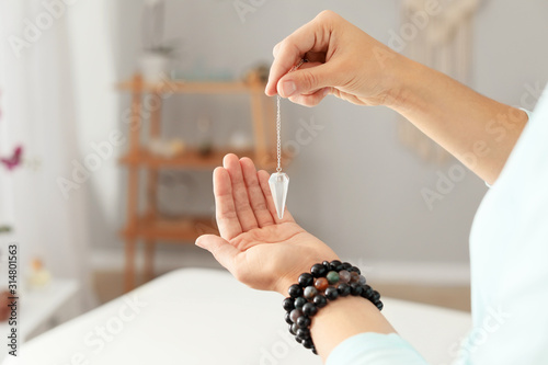 Reiki master with biolocation pendulum, closeup photo