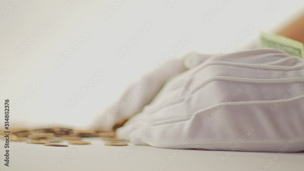 White-gloved hands scooping up a pile of gold coins. They sort out and scatter money.On white background. Garland. Money glitters.