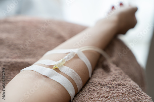 Patient with intravenous drip .receiving saline solution. Injecting needle in to the arm.