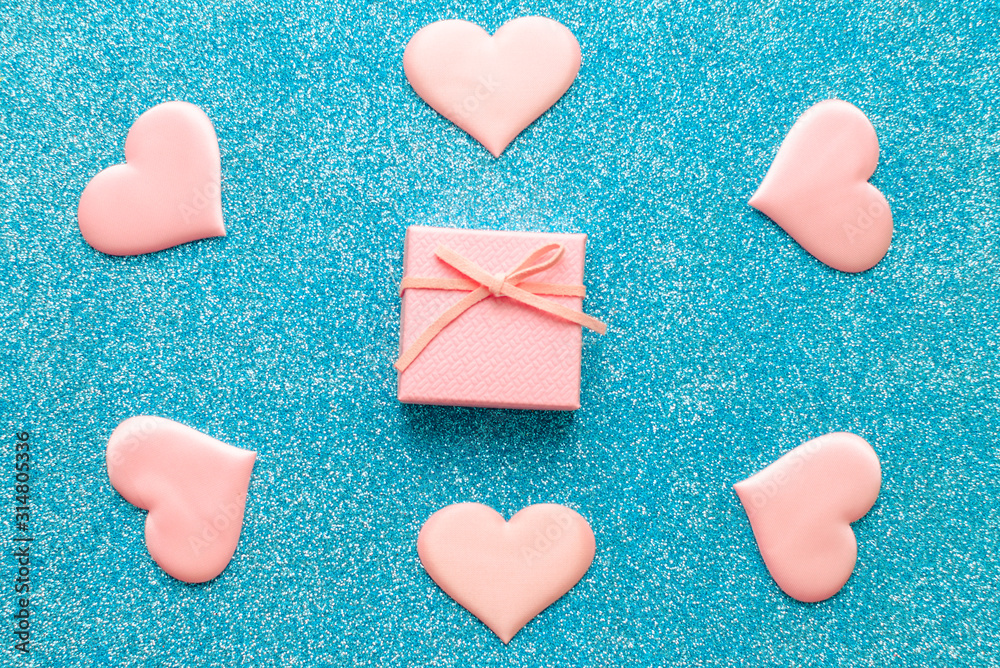 Obraz premium Valentines day pattern background flat lay pink hearts and a pink gift box with rose ribbon on a glittering classic blue background with copy space. love wedding romantic concept, minimal top view