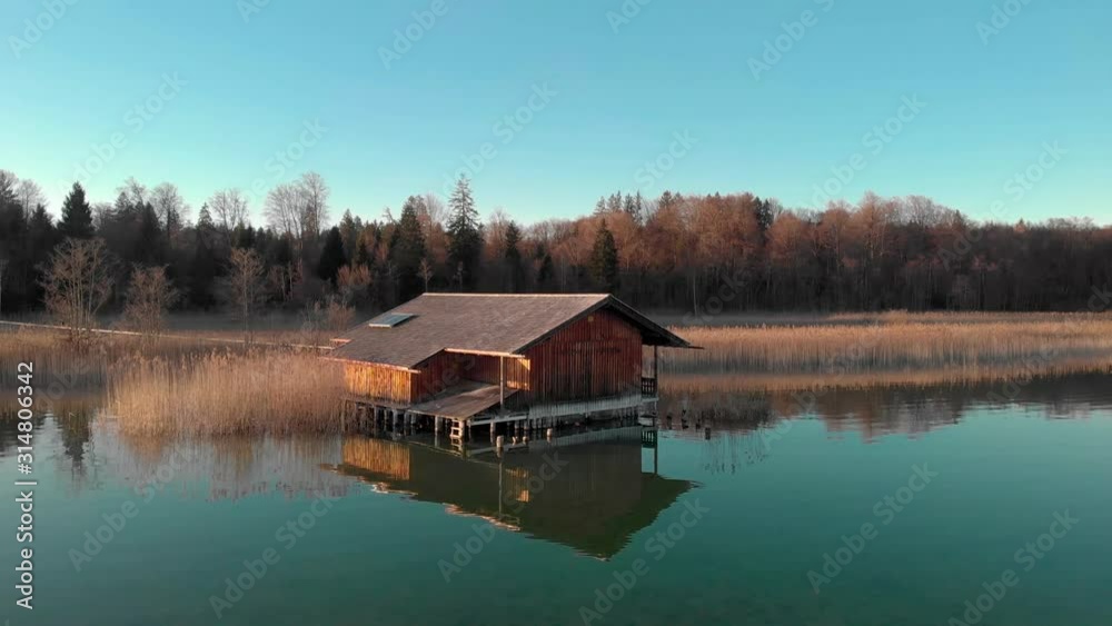 A low Drone shot of a Hut on a lake with less sun during sunset A low Drone shot of a Hut on a lake with less sun during sunset