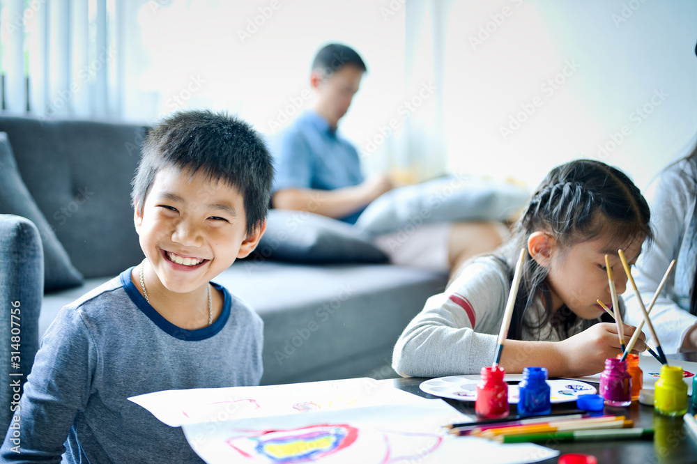 Asian family with cute daughters and sun painting art in living room at home Asian family with cute daughters and sun painting art in living room at home