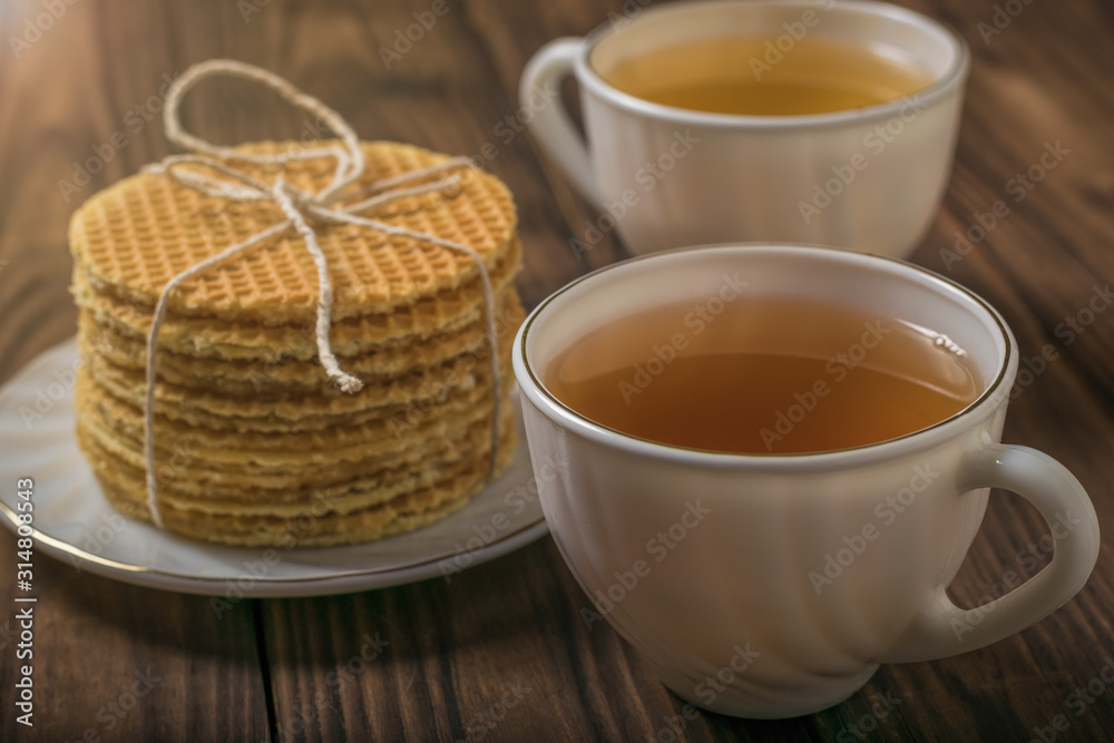 Two cups of tea and homemade waffles on a wooden table. Two cups of tea and homemade waffles on a wooden table.