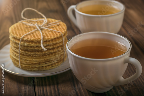 Two cups of tea and homemade waffles on a wooden table.