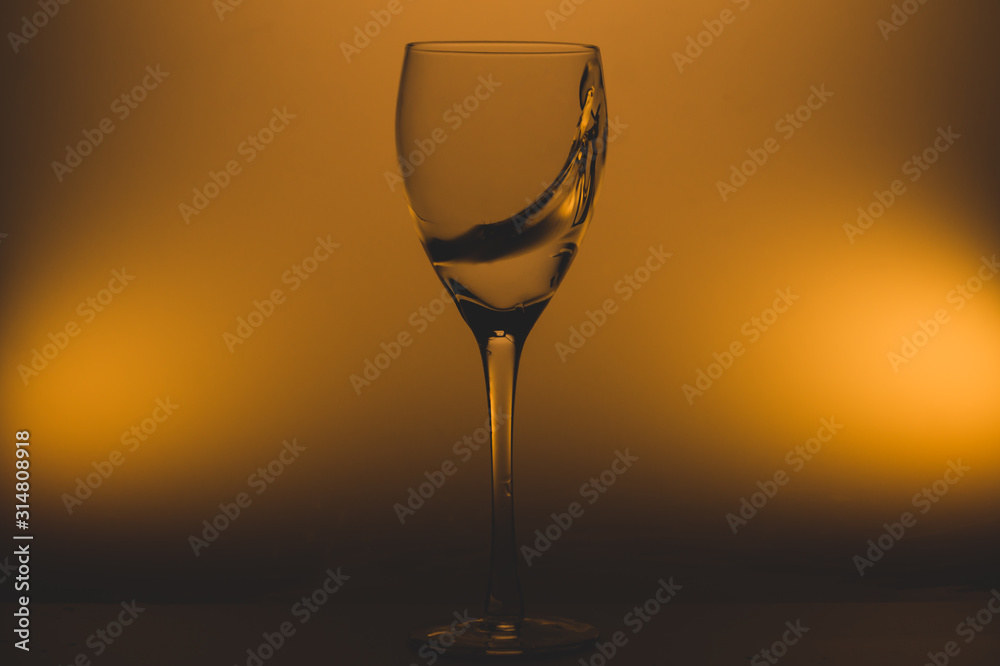 Water splash in glass on glowing background. splashing water in wine glass