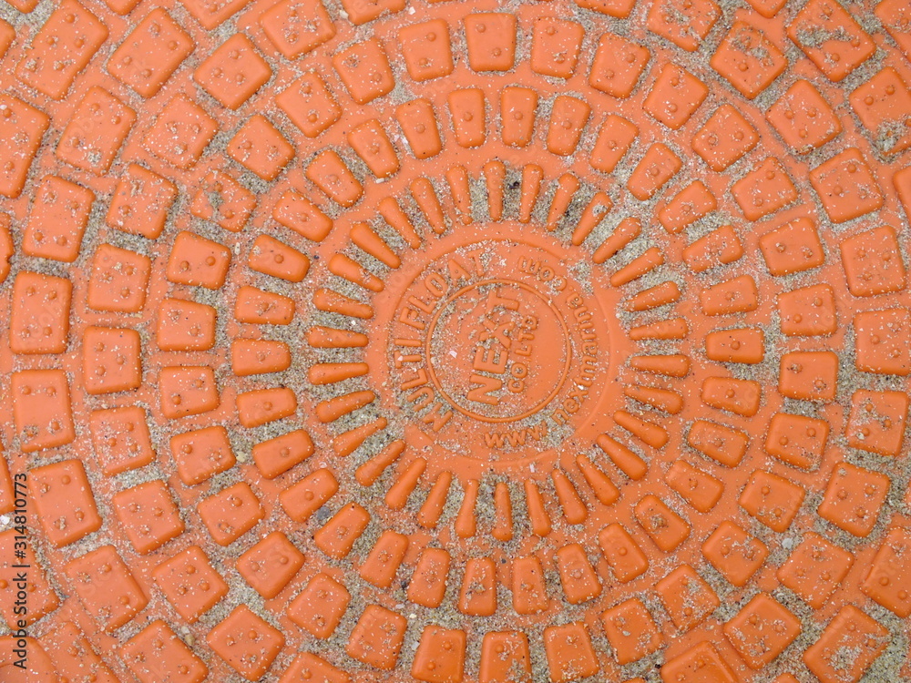  macro image of a bright orange plastic embossed manhole cover 