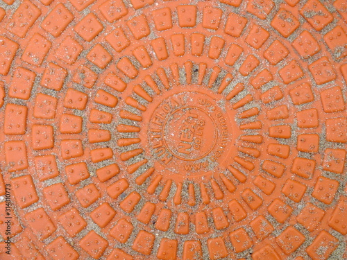  macro image of a bright orange plastic embossed manhole cover 