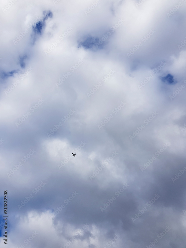 Tiny plane on a background of white coluds sky Tiny plane on a background of white coluds sky