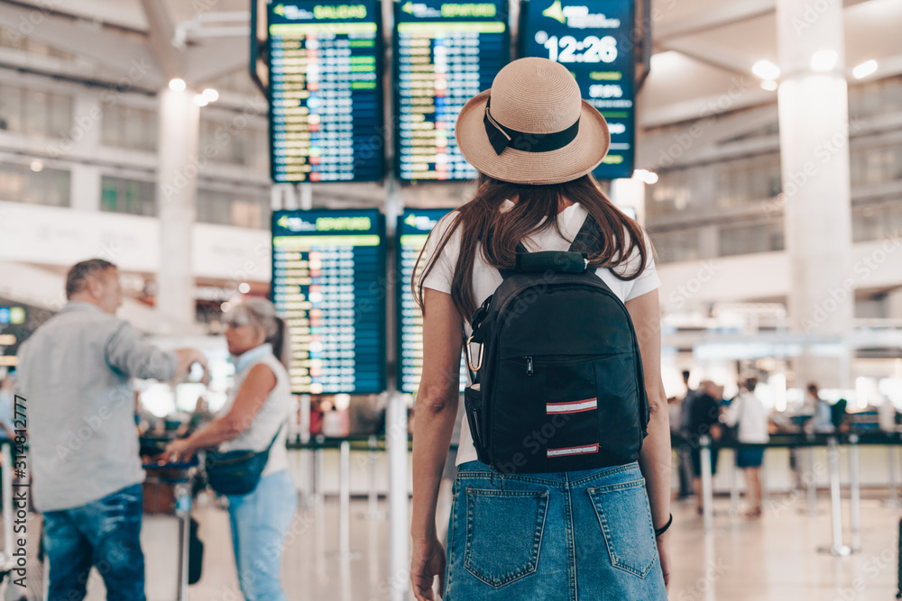 tourist with a backpack and a hat at the airport looks at the arrival board tourist with a backpack and a hat at the airport looks at the arrival board