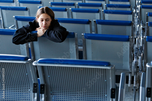Teenage girl sitting at the empty waiting hall of an airport