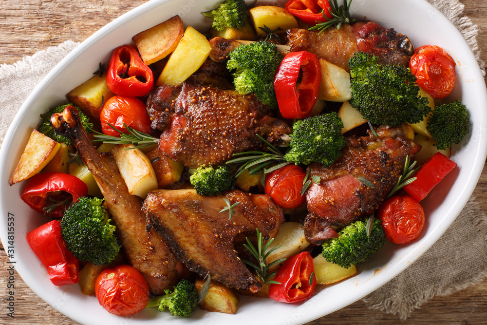 Baked chicken recipe with potatoes, broccoli, tomatoes and sweet pepper close-up in a baking dish. Horizontal top view Baked chicken recipe with potatoes, broccoli, tomatoes and sweet pepper close-up in a baking dish. Horizontal top view