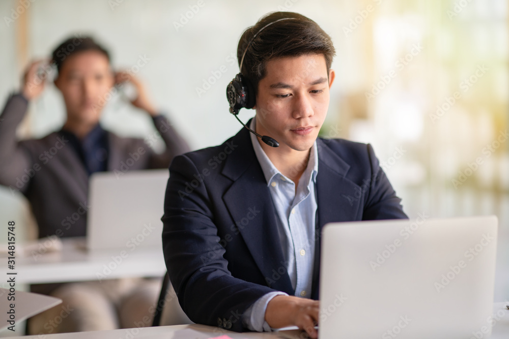 Young handsome male customer support phone operator with headset working in call center. Young handsome male customer support phone operator with headset working in call center.