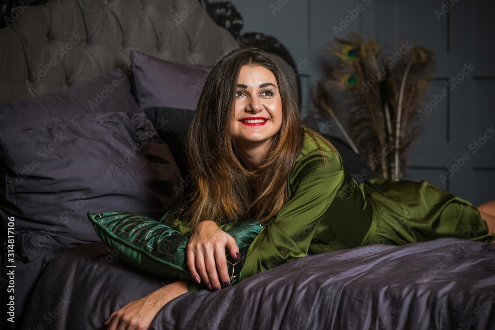 Fototapeta premium Woman in dark boudoir interior and silk green robe