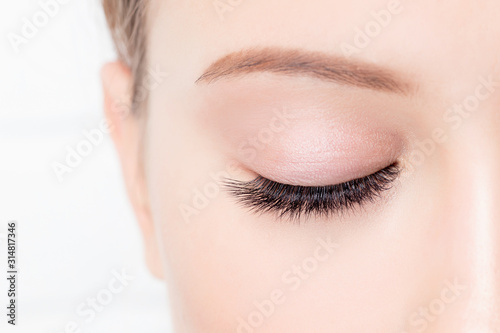 Closed female eye with beautiful makeup and long lashes on white background. Concept eyelashes extensions procedure photo