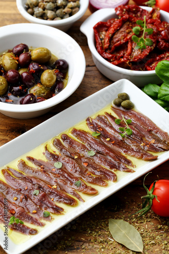 cibo mediterraneo spunti con acciughe pomodori secchi olive sfondo rustico photo