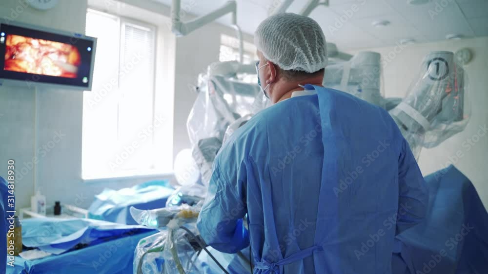 Endoscopic operation in surgery room. Surgeon man looks at the screen where the process of endoscopic operation is depicted. Modern technologies in medicine.