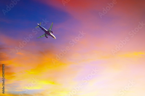 Passenger plane flying in colorful sky at sunset