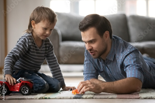 Loving dad play cars with little son at home