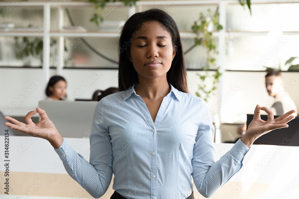 Obraz premium Biracial woman office worker take break during meditating avoid stress