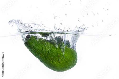 A Avocado splashing into water against a white background