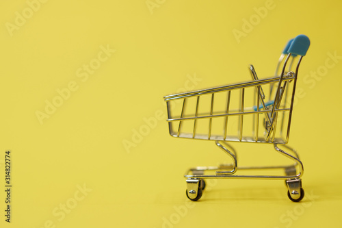 shopping trolley on yellow background with some copy space
