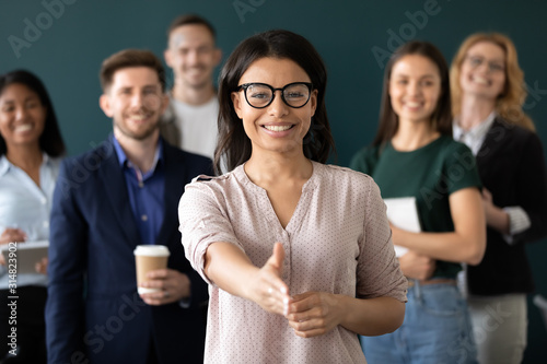 Mixed race woman sales manager stretch out hand greeting client photo