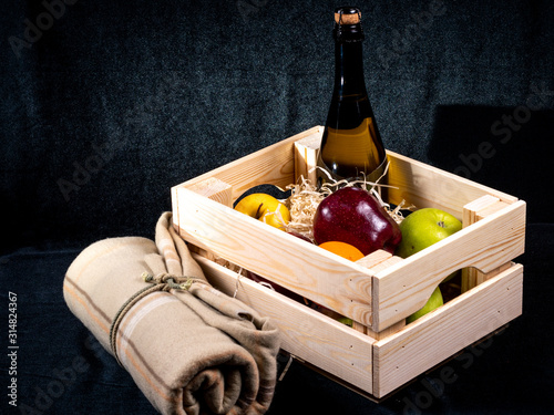 Wooden gift box with fruit, sparkling wine and plaid