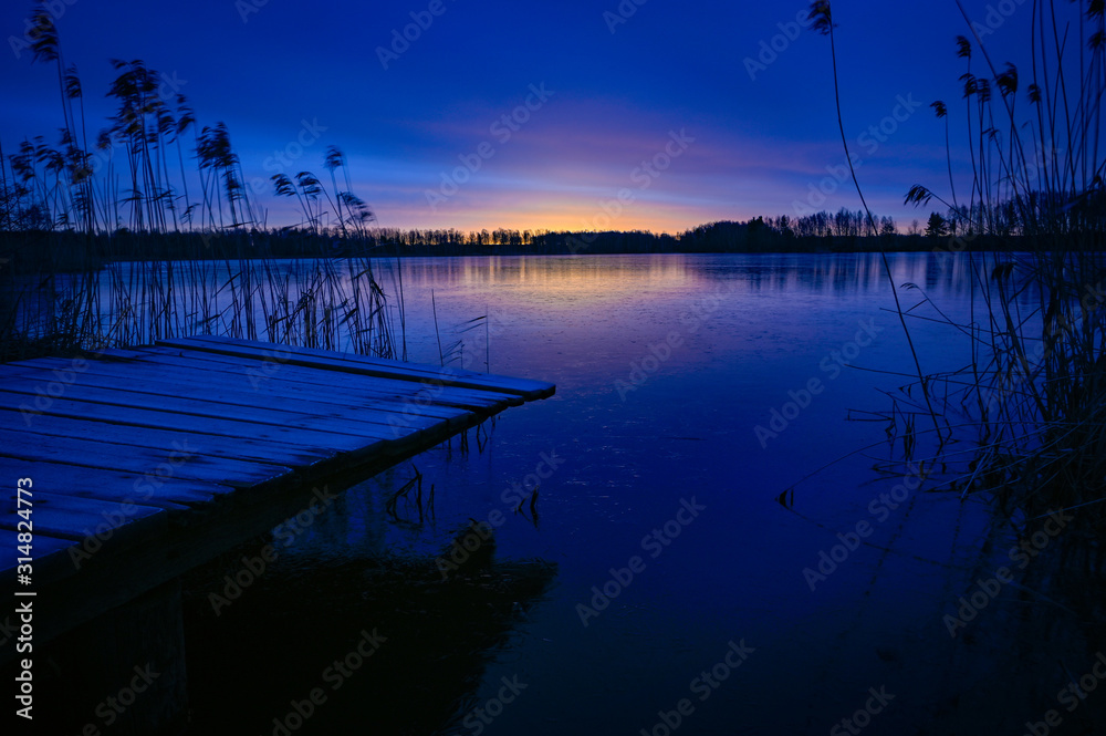 Fototapeta premium sunrise over wooden jetty and frozen lake