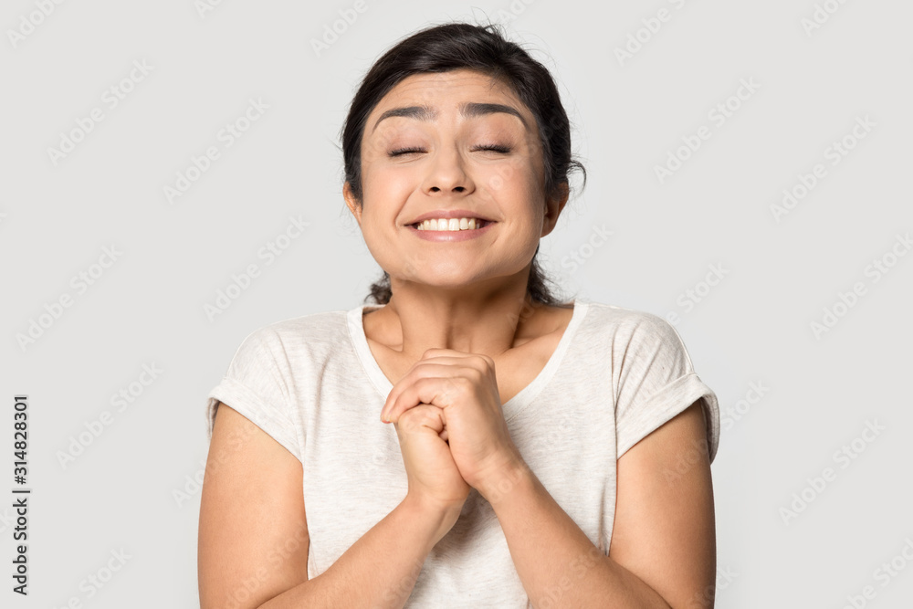 Millennial indian ethnicity happy girl praying for dream come true. Millennial indian ethnicity happy girl praying for dream come true.