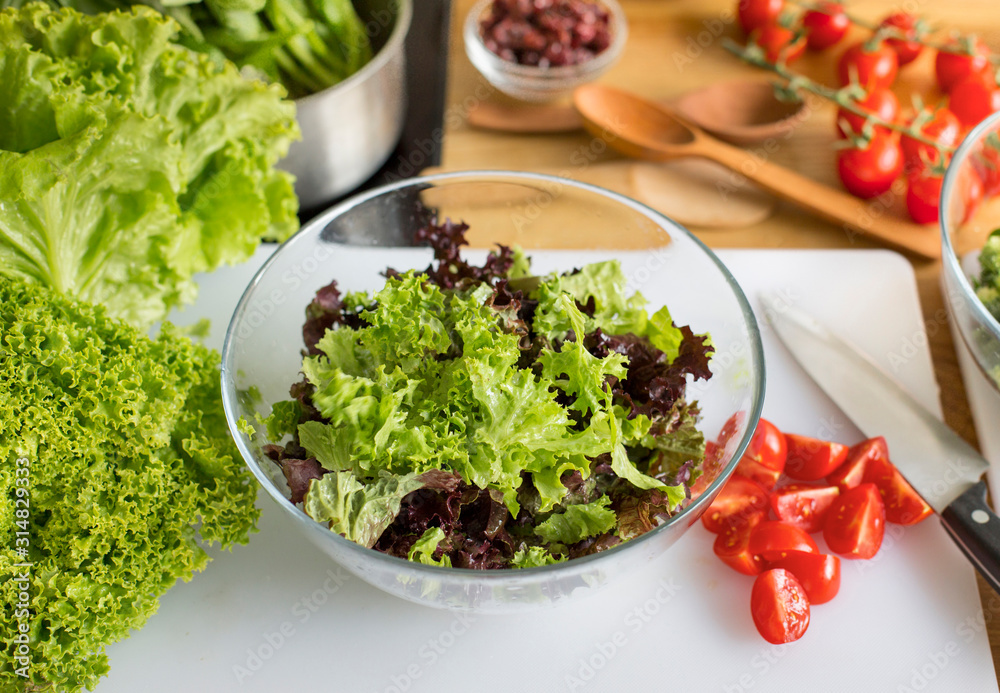 Glass bowl with fresh salad on the kitchen table Glass bowl with fresh salad on the kitchen table