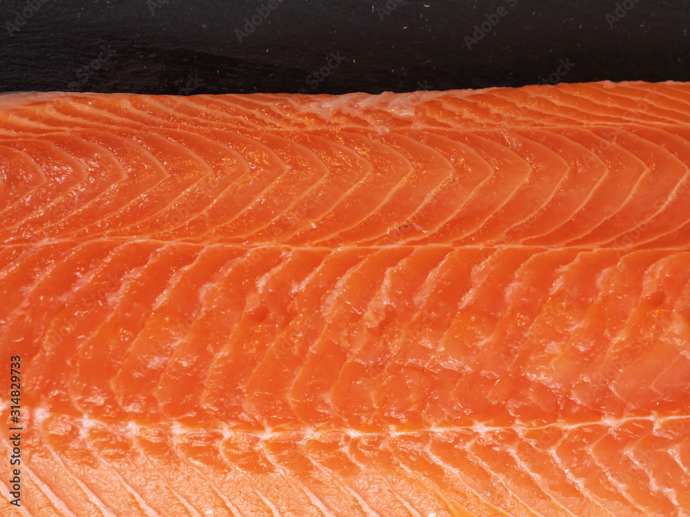 Slice of raw oily salmon fillet on stone plate. Close up. Slice of raw oily salmon fillet on stone plate. Close up.