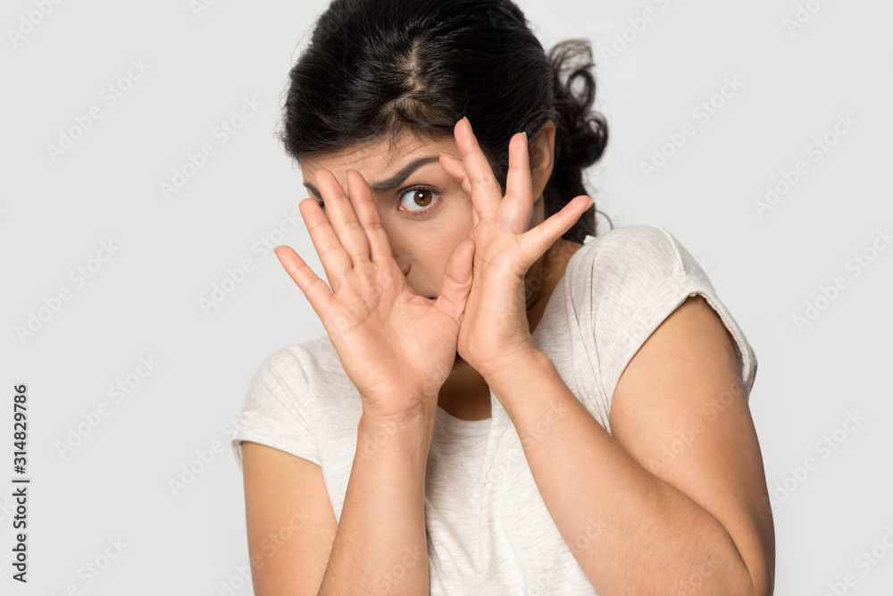 Young indian afraid terrified woman hiding behind hands. Young indian afraid terrified woman hiding behind hands.