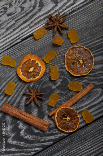 Jelly chewing sweets. Dried slices of orange, cinnamon sticks and anise stars. Scattered on brushed pine boards painted in black and white.