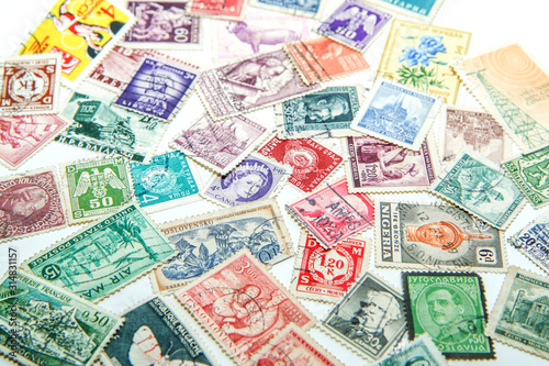 An assorted mixture of the old european and world stamps is lying on the table. Stamps are colorful and various. 