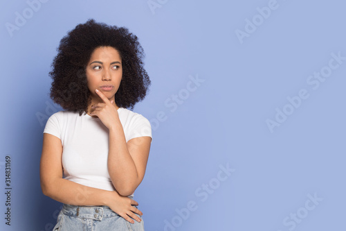 Doubtful african american young lady looking away on empty space.