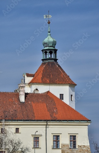 A view of a part of a historic castle with a red roof and with the tower in Smečno in Bohemia